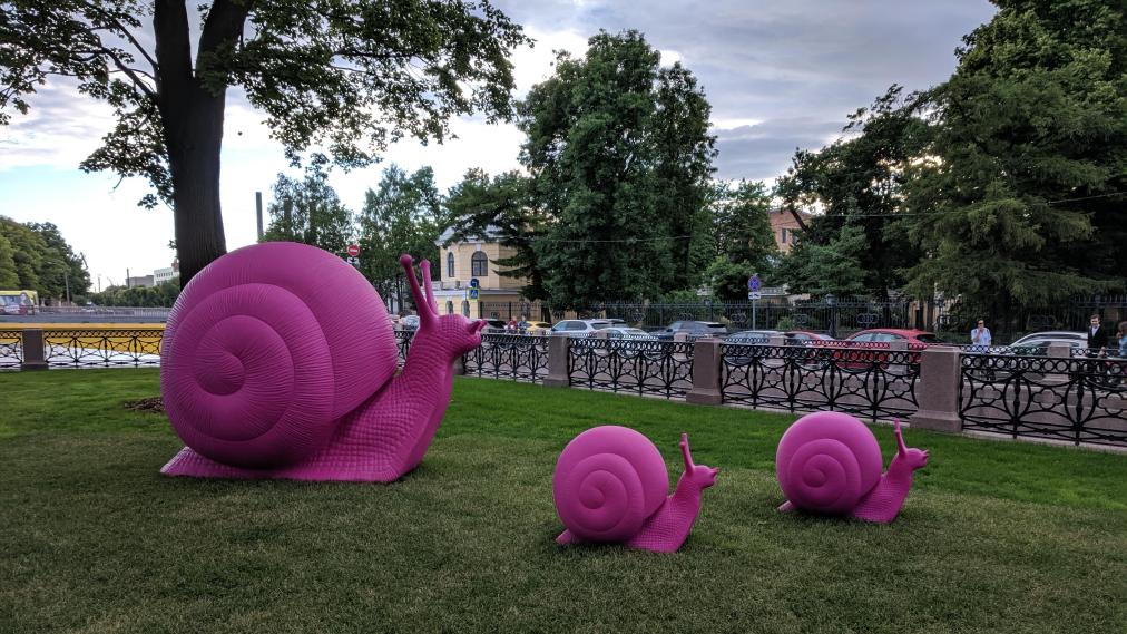 Three large pink snail sculptures on a lawn